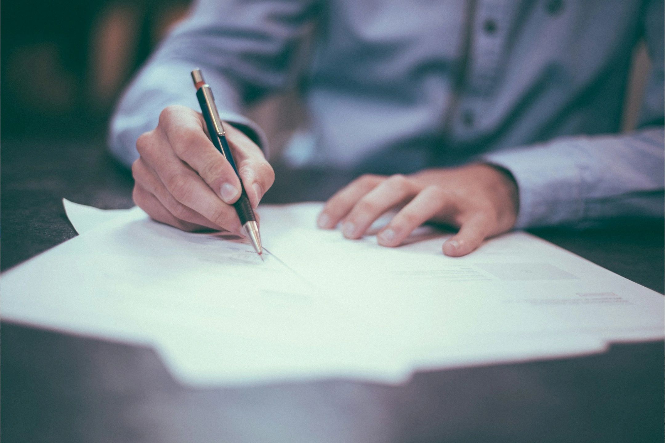 Hands signing a business document